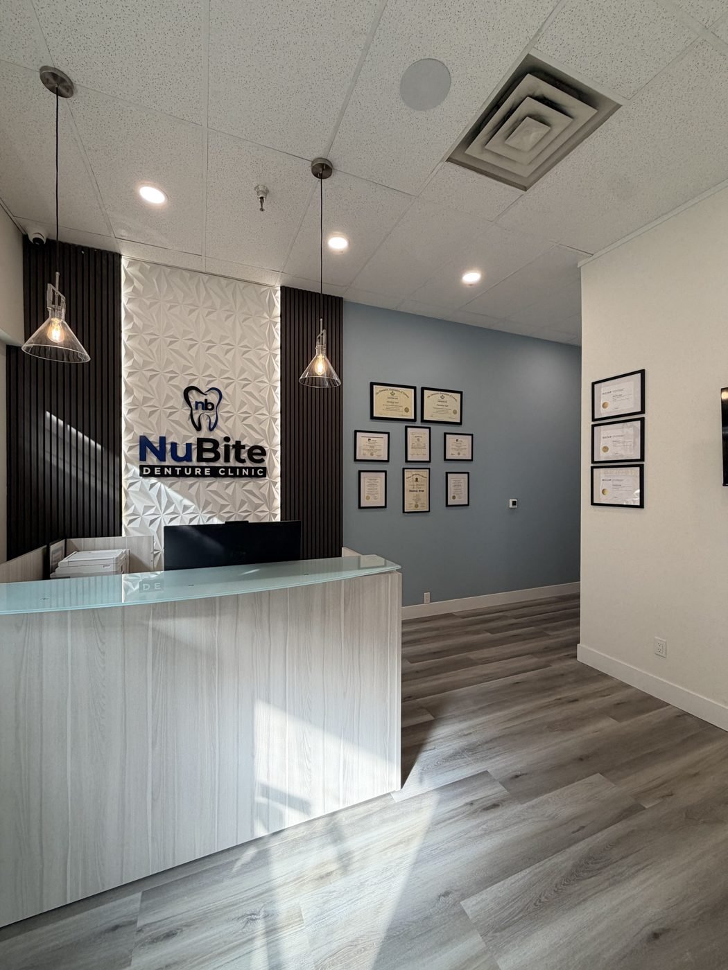 Reception desk, NuBite Denture Clinic sign and registered denturist certificates at NuBite Denture Clinic in Langley, BC
